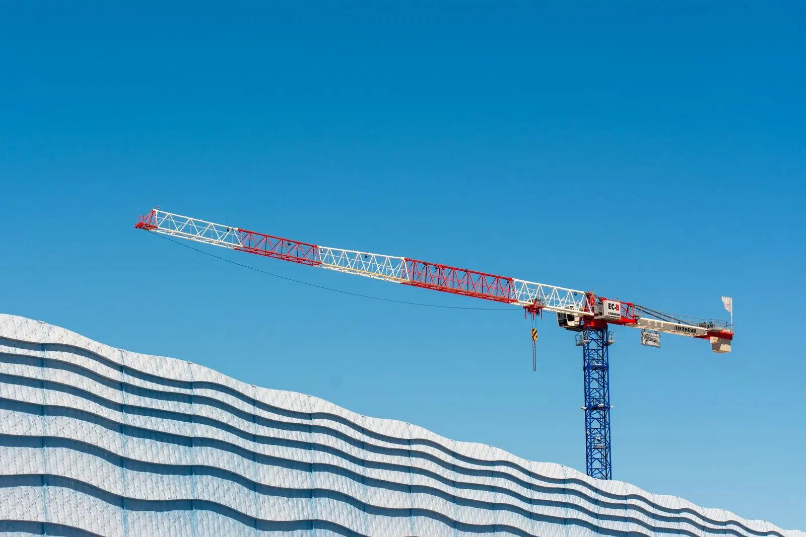 Grúa de construcción junto a la fachada de un edificio industrial en expansión