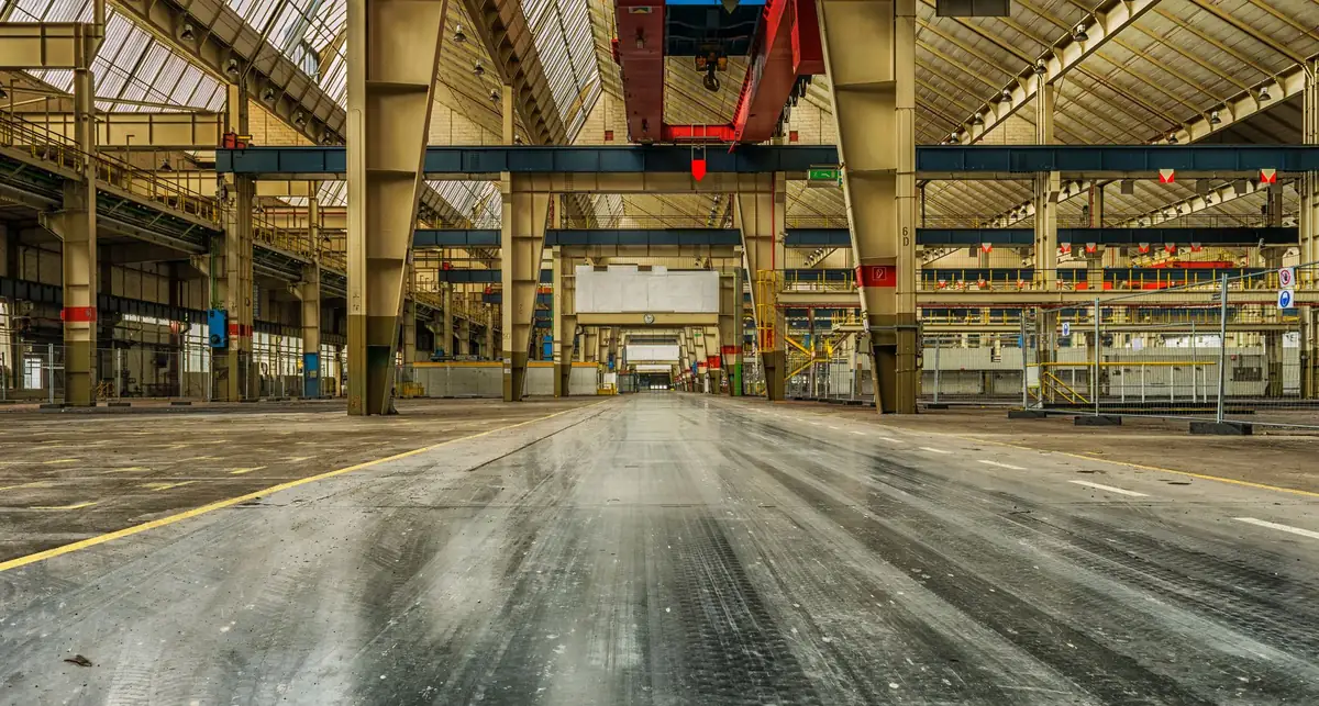 Interior de nave industrial vacía con grúa viajera y estructura de acero
