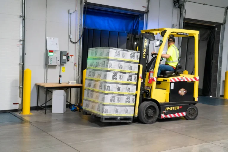 Trabajador operando un montacargas amarillo dentro de una bodega industrial