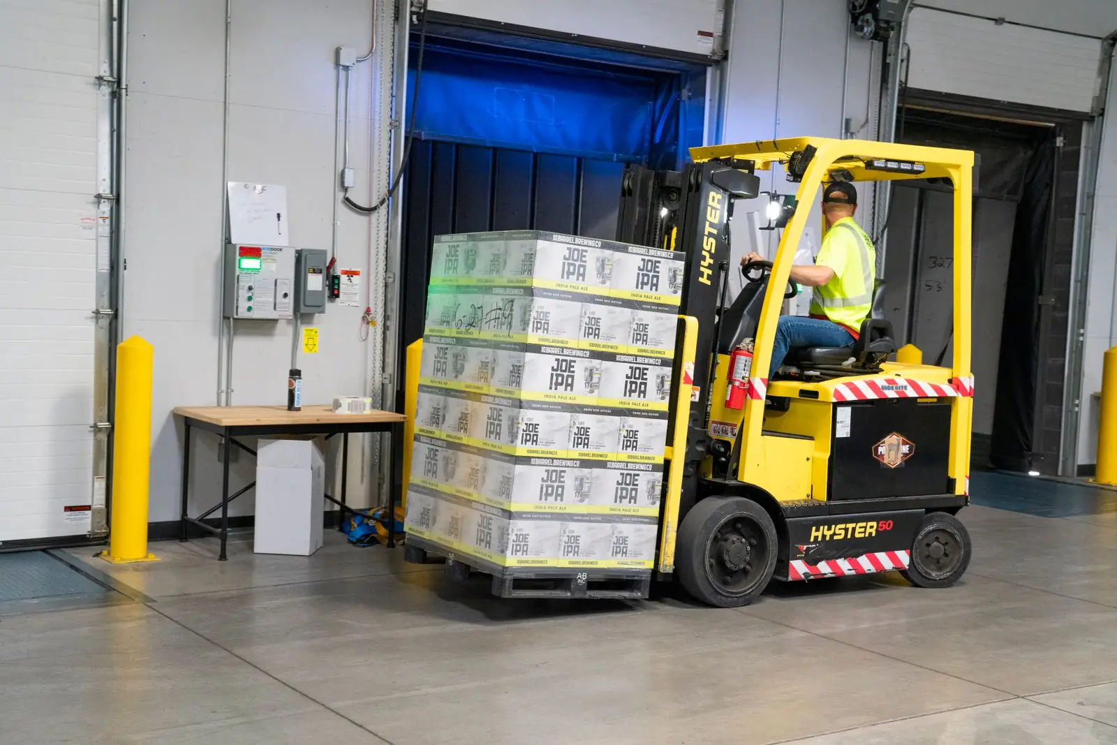 Trabajador operando un montacargas amarillo dentro de una bodega industrial