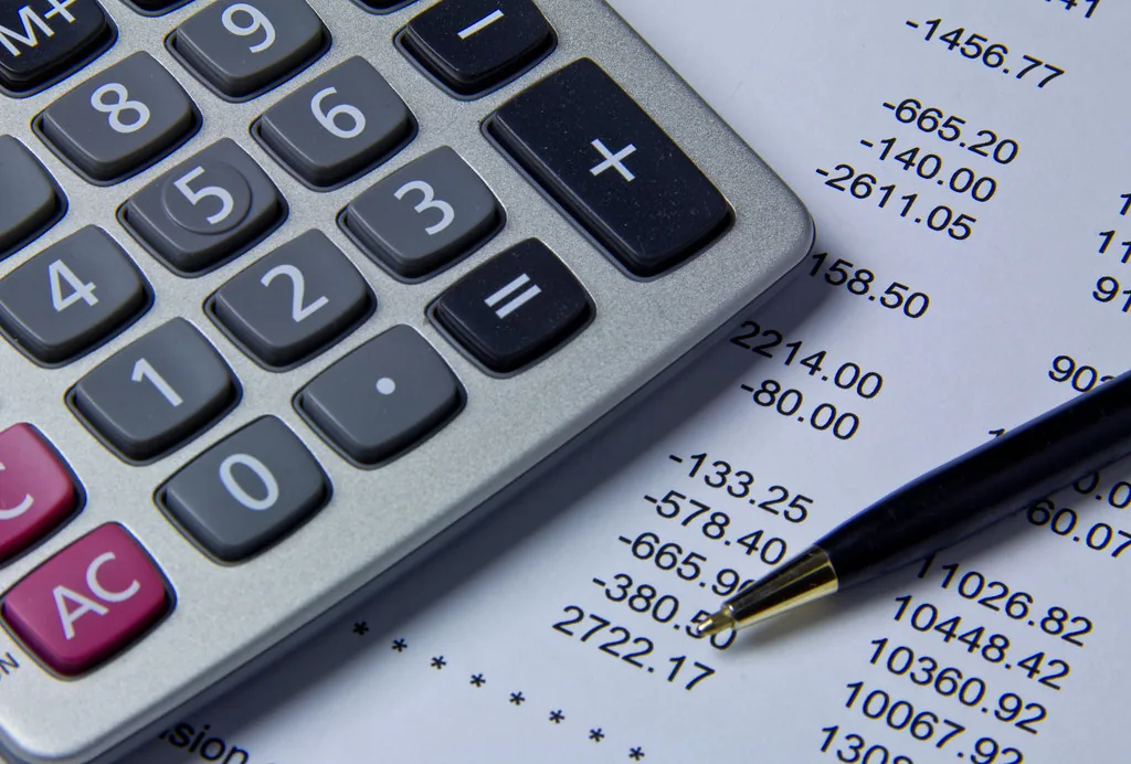 Calculadora y pluma sobre un reporte contable con cifras positivas y negativas
