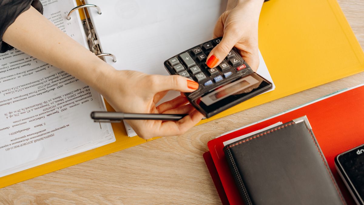 Manos usando una calculadora sobre documentos contables en un escritorio
