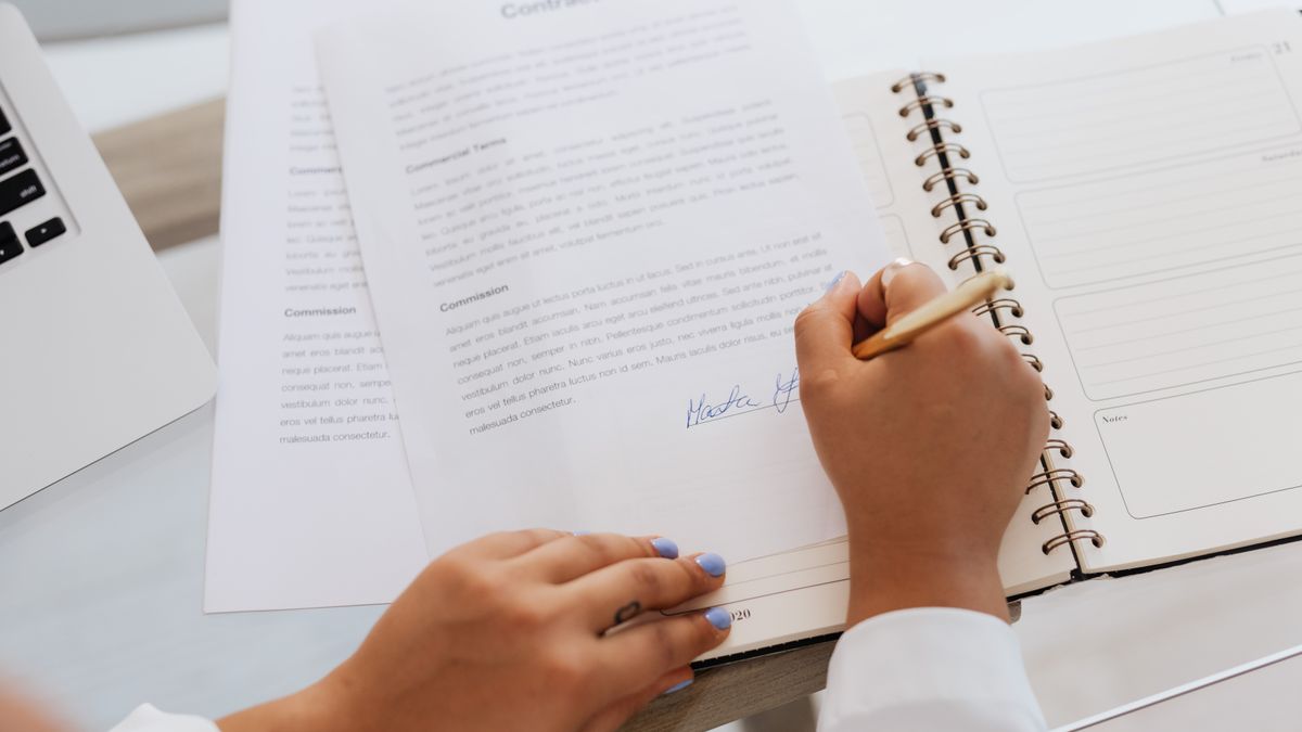Manos firmando un contrato sobre un escritorio de oficina