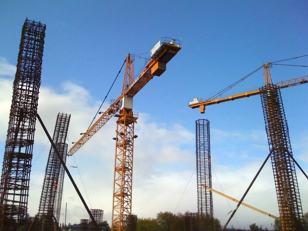 Grúas torre y estructuras de acero en una obra bajo cielo azul