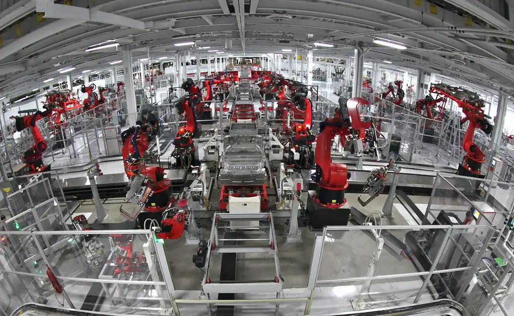 Línea de ensamble automotriz con brazos robóticos soldando carrocerías