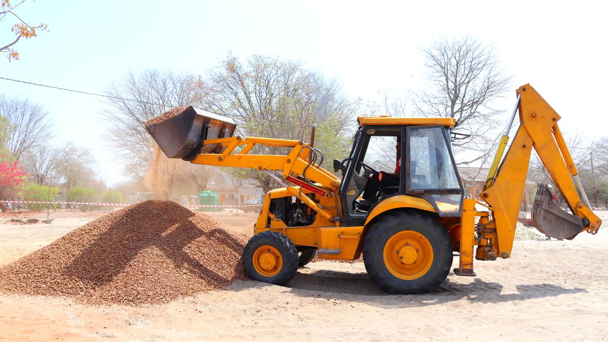Excavadora amarilla moviendo grava en una obra