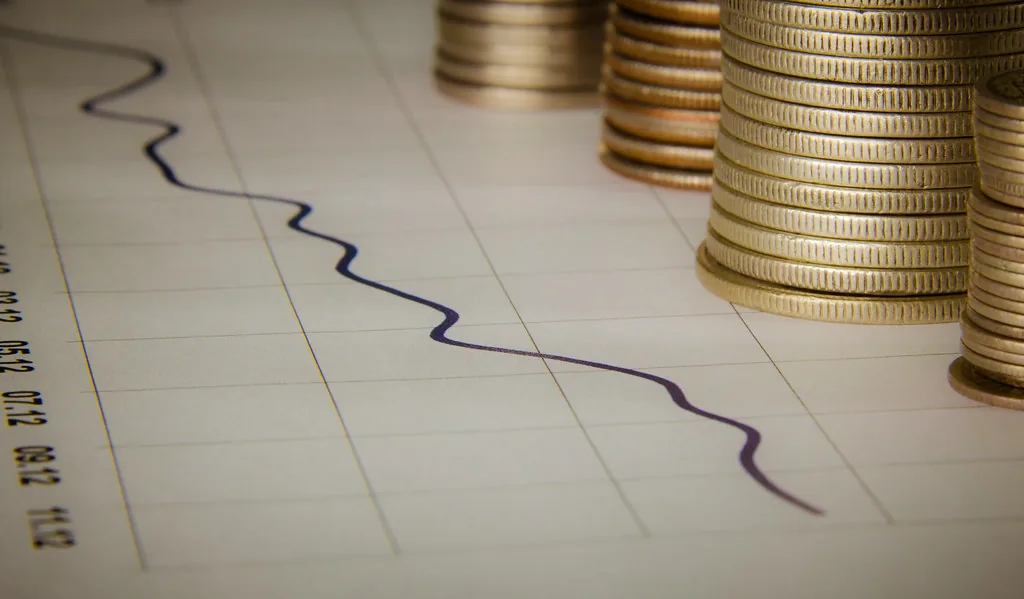 Pilas de monedas junto a una gráfica de rendimiento en papel