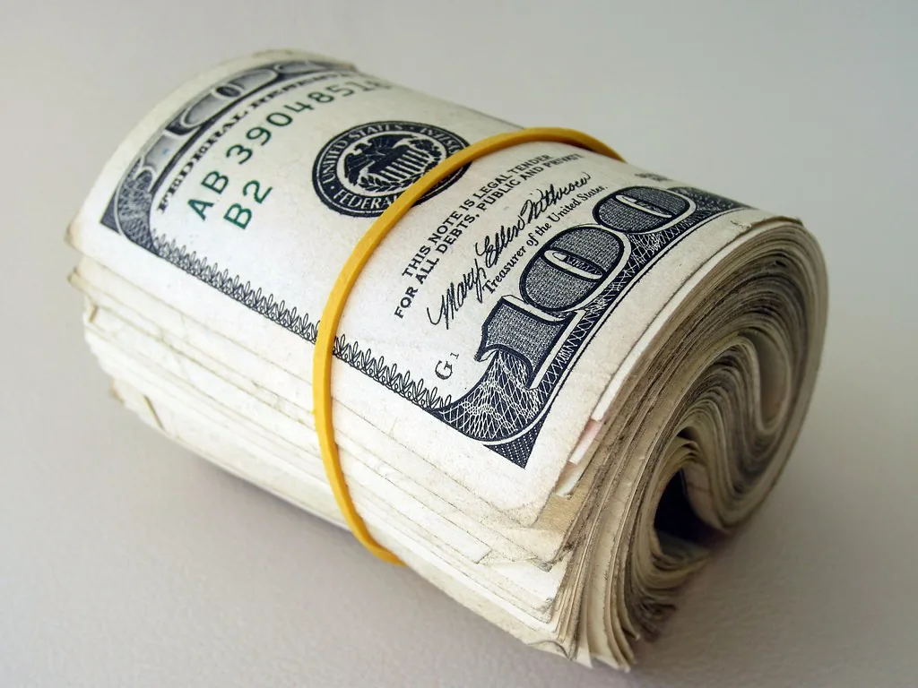 Rollo de billetes de cien dólares sujeto con una liga